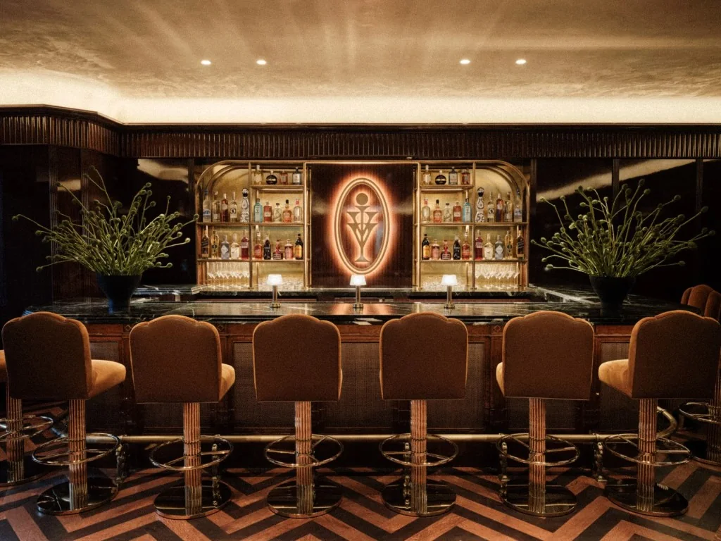 Brass-trimmed bar with velvet stools and a chevron floor at Kith Ivy