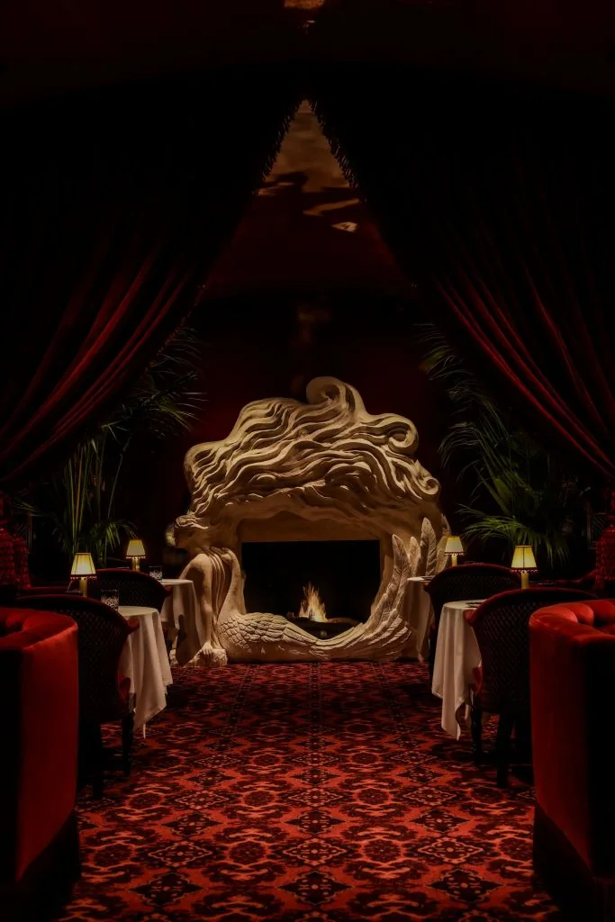 Red lounge with a fireplace and sofas at Chez Margaux in New York