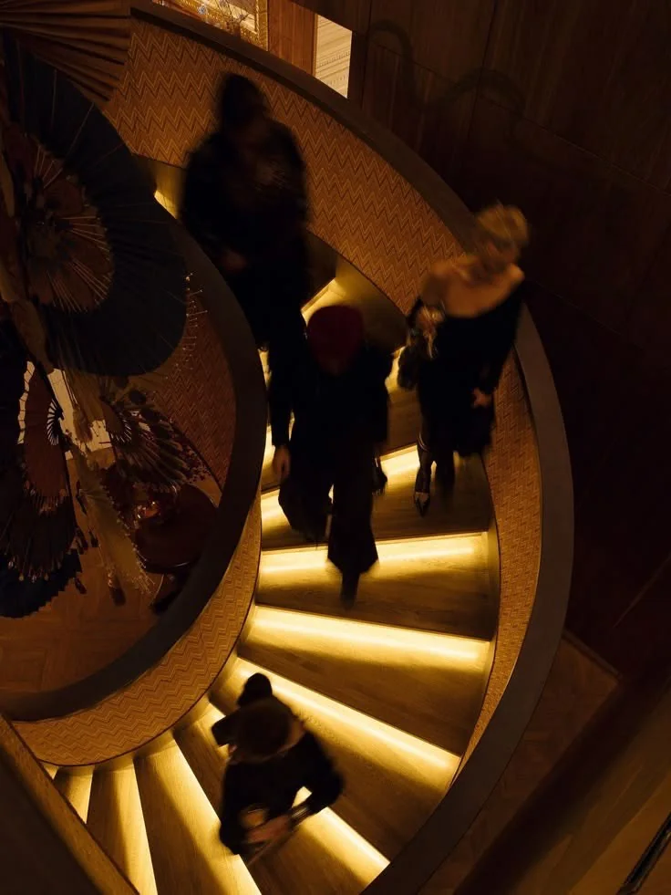 A curved staircase illuminated by warm amber lighting